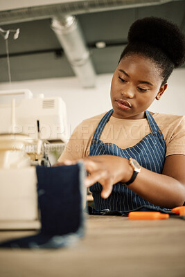 African american tailor sewing fabric. Young designer stitching denim material. Fashion designer using a sewing machine in her studio. Creative businesswoman working in her design studio