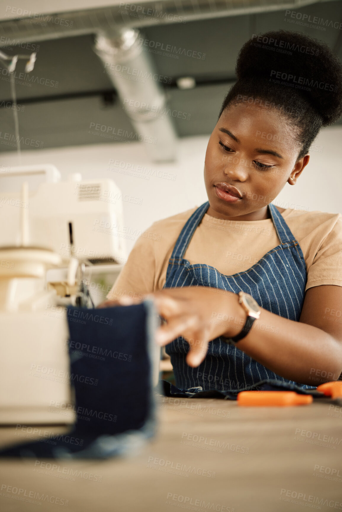 Buy stock photo African american tailor sewing fabric. Young designer stitching denim material. Fashion designer using a sewing machine in her studio. Creative businesswoman working in her design studio