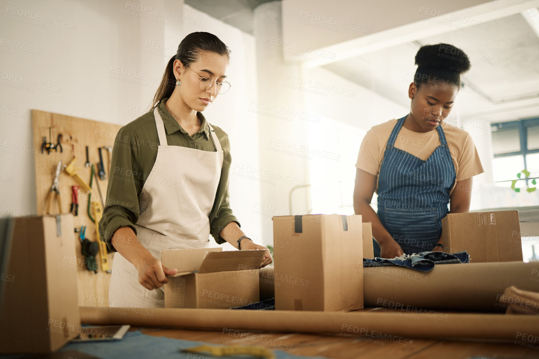 Buy stock photo Two fashion designers unpacking boxes. Business colleagues collaborating to unpack stock. Coworkers opening packages. Tailors unpacking fabric samples. Two seamstresses unpack orders