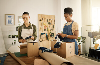 Buy stock photo Two colleagues unpacking boxes. Fashion designers unpack stock order together. Colleagues unpacking boxes together. Seamstresses packing boxes of material samples. Coworkers packing denim samples