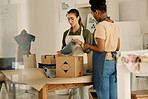 Two colleagues unpacking boxes. Fashion designers packing stock order together. Tailors unpacking boxes of denim fabric. Businesswoman packing a box of material samples with coworker.