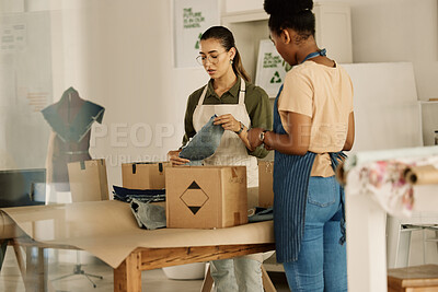 Buy stock photo Two colleagues unpacking boxes. Fashion designers packing stock order together. Tailors unpacking boxes of denim fabric. Businesswoman packing a box of material samples with coworker.
