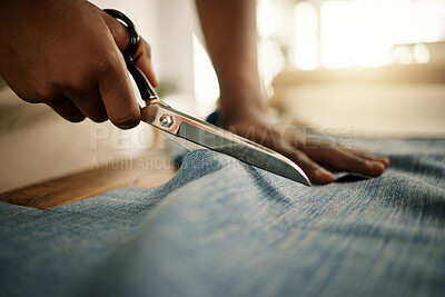 Fashion designer cutting a textile sample. Creative tailor cutting denim fabric with a scissor. Closeup of hands of seamstress cutting material for his design. Business owner working in a studio