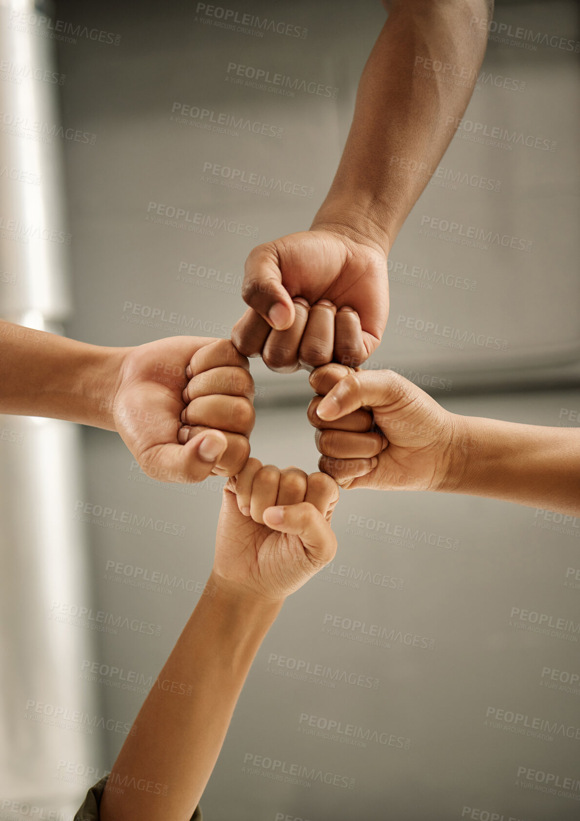 Buy stock photo Closeup of hands of colleagues with fists joined. Zoom into hands of coworkers fists joined from below. Group of businesspeople with fists together in a circle. A united group of entrepreneurs