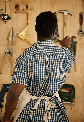 Buy stock photo Back of carpenter picking a tool from his wall. African American entrepreneur deciding on a tool. Creative businessman picking a tool from his wall. Carpenter reaching for a tool from his collection
