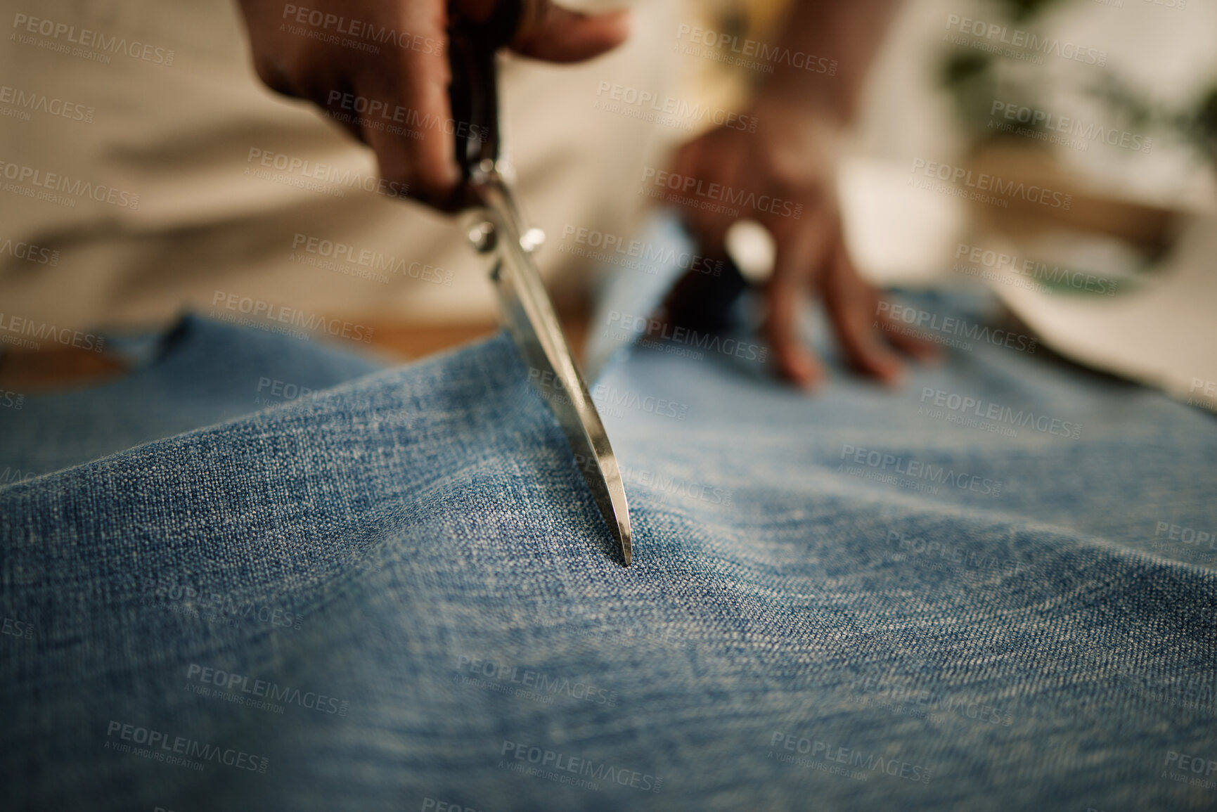 Buy stock photo Closeup of hand of fashion designer using a scissor to cut a fabric sample. Tailor cutting a piece of denim material. Seamstress cutting into a piece of material. Entrepreneur working in a studio