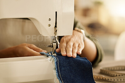 Buy stock photo Closeup of the hand of a seamstress using a sewing machine. Fashion designer sewing denim fabric on a machine. Tailor using a sewing machine. Creative entrepreneur stitching a piece of material