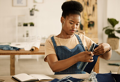 Buy stock photo Creative designer holding denim fabric and a pen. Young tailor making notes about a textile sample. African American entrepreneur looking at a material sample. Fashion designer working in a studio