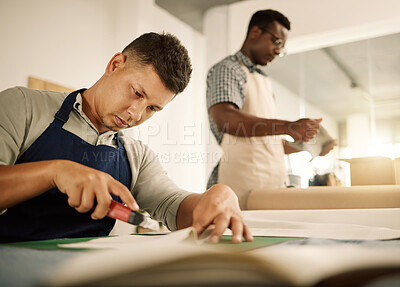 Buy stock photo Focused tailor using knife to cut a piece of fabric. Mixed race designer trimming a piece of material. Young businessman working in a design studio. Seamstress cutting a fabric sample