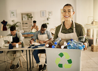 Buy stock photo Cheerful seamstress holding a bucket of recycled plastic bottles. Mixed race designer holding bin of renewable plastic bottles. Young tailor recycling plastic bottles from her studio