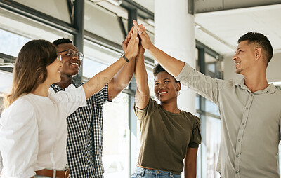 Buy stock photo Cheerful creative business team standing in office and giving high five while celebrating a win. Diverse business people standing together at startup
