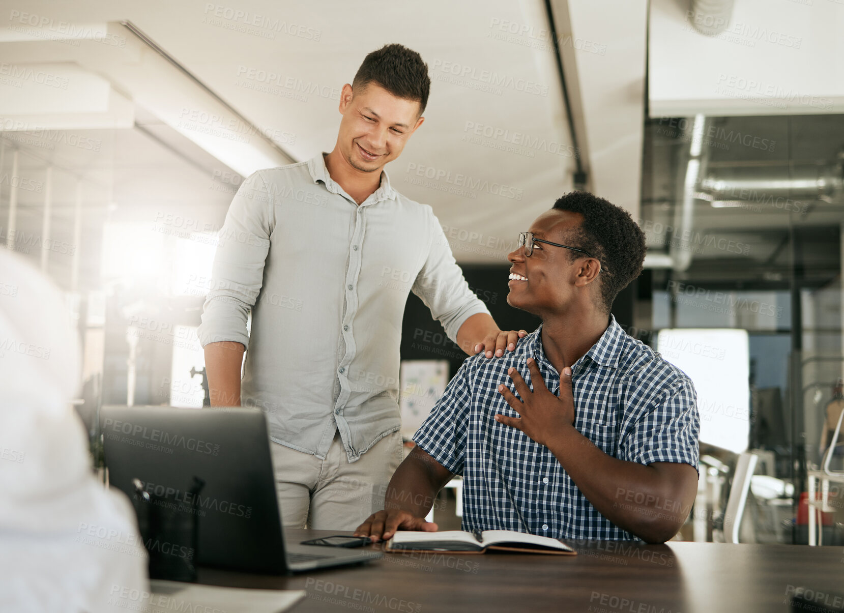 Buy stock photo Two diverse businessmen talking at a desk discussing new project on laptop. Mentor complimenting colleague on a job well done and being a fast learner in modern office