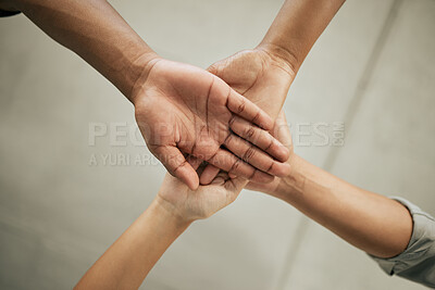 Buy stock photo Close up of four colleagues putting hands together in the office. Creative team joining hands and showing unity through teamwork