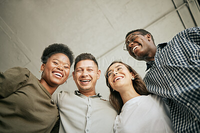 Buy stock photo Team of happy united young business people hugging each other. Diverse mixed race group of men and women standing in row in their office, huddling and laughing together