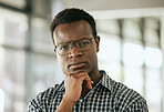 Portrait of a serious young professional african american business man with glasses and hand on chin standing in an office and looking at camera