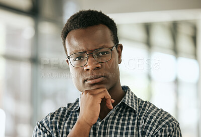 Portrait of a serious young professional african american business man with glasses and hand on chin standing in an office and looking at camera