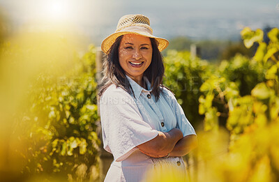 One smiling mature mixed race confident farmer standing with her arms crossed on her vineyard with copyspace. Hispanic mature woman with her arms folded on a wine farm and wearing sunglasses in summer