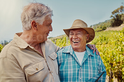 Two happy senior farmers standing and embracing on their vineyard. Smiling elderly Caucasian and mixed race men and colleagues bonding and laughing together on a wine farm in summer before harvest