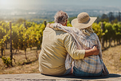 Rearview of unknown senior couple sitting with their arms around each other on their farm. Caucasian farmers bonding while admiring their vineyard and embracing. Elderly husband and wife hugging