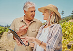 Two happy senior farmers standing and talking while using digital tablet on a vineyard. Smiling elderly man and woman bonding on a wine farm in summer before harvest. Elderly couple standing together