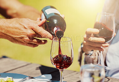 Buy stock photo Closeup of unknown farmer pouring red wine into wineglass on farm for friends. Caucasian man holding bottle and filling glass with alcohol for tasting during summer on vineyard. Weekend wine tasting