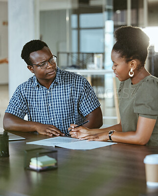 Two african american businesspeople having a meeting and looking at a report together at work. Businessman and businesswoman taking notes while talking in an office