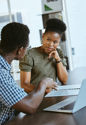 Two businesspeople having a meeting and looking at a report together at work. Businessman showing a black female colleague a document while talking in an office
