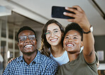 Group of young cheerful businesspeople taking a selfie together at work. Happy african american businesswoman taking a picture with her colleagues on her phone in an office
