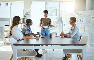 Buy stock photo Group of diverse businesspeople having a meeting in an office at work. Happy african american businesswoman holding a report and talking while doing a presentation at a table for coworkers. Businesspeople planning together