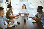 Group of diverse businesspeople having a meeting in an office at work. Happy mixed race businesswoman talking during a workshop at a table with coworkers. Businesspeople planning together