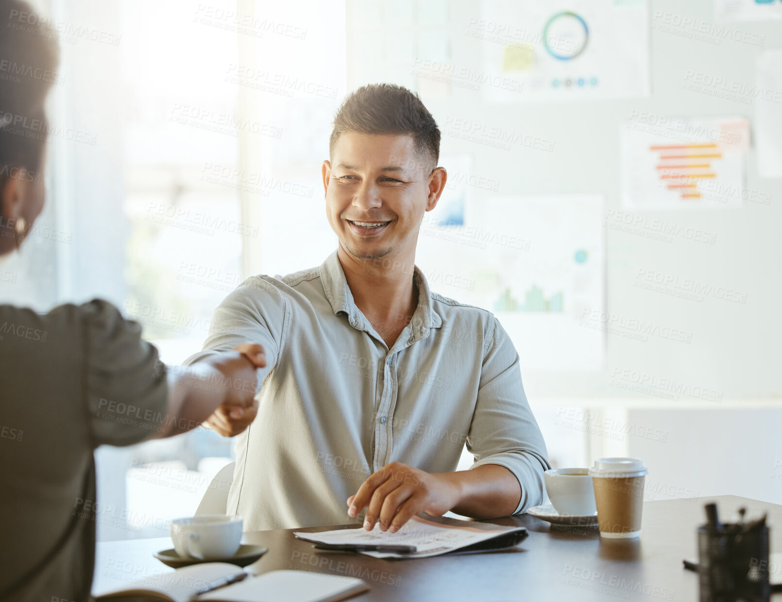 Buy stock photo Two businesspeople shaking hands while in an office together at work. Business professionals greeting and making deals with each other. Hispanic boss hiring an employee in an interview