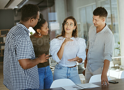Buy stock photo Group of businesspeople standing and talking together in an office. Hispanic businesswoman doing a presentation on a report to her colleagues in a meeting