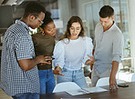 Group of focused businesspeople standing and talking together in an office. Hispanic businesswoman doing a presentation on a report to her colleagues in a meeting at work
