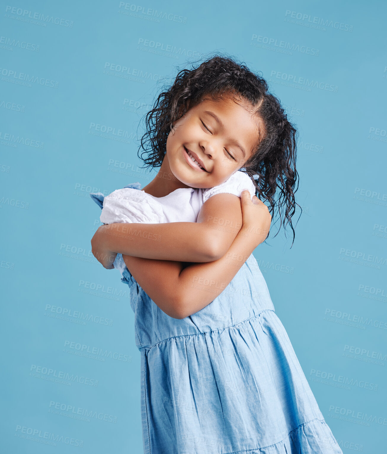 Buy stock photo Adorable loveable little girl looking happy while hugging embracing herself. Cute kid with positive self-esteem against blue studio background