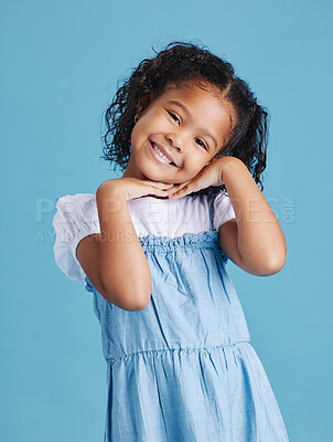Portrait of happy smiling little girl posing with her hands under her face showing a healthy dental smile against blue studio background. Cute mixed race kid in casual clothes