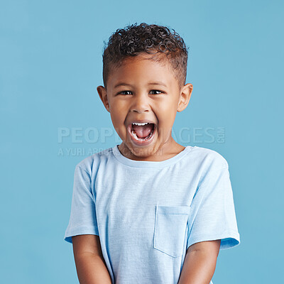 Buy stock photo Close up of excited little boy looking happy and shouting while standing against a blue studio background. Cute preschooler wearing casual clothes
