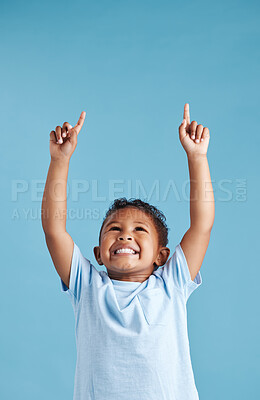 Buy stock photo Excited little hispanic boy kid looking and pointing his fingers up at copy space against blue studio background. Happy preschooler advertising childrens products