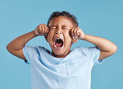 Buy stock photo Unhappy little hispanic boy looking upset and crying while rubbing his eyes against a blue studio background. Unhappy preschooler kid bawling his eyes out