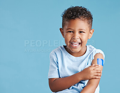 Buy stock photo Portrait, happy and kid with plaster in studio isolated on a blue background mockup space. Face, smile and boy child with bandage after vaccine, injury or wound for healthcare, first aid and excited.