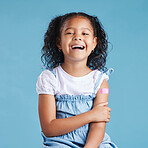 Happy vaccinated little girl kid showing arm with adhesive bandage after vaccine injection standing against a blue studio background. Advertising vaccination against coronavirus. Child immunisation