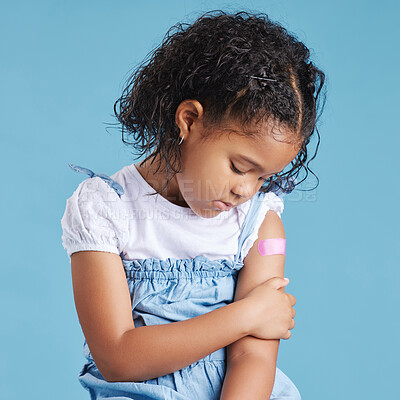 Upset, sad little girl shows vaccinated arm with adhesive bandage after being injected with Covid-19 vaccine, motivates to vaccinate against coronavirus to stop epidemic. Children immunization