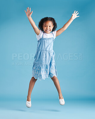 Happy young adorable little hispanic girl jumping in the air, isolated on blue background. Funny preschooler kid expressing her excitement and having fun