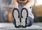 Closeup of one active caucasian woman touching her feet and stretching legs for warmup to prevent injury while exercising in a gym. Bottom sole of shoes of female athlete preparing for training workout in a fitness centre