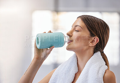 Buy stock photo One fit young caucasian woman taking a rest break to drink water from bottle while exercising in a gym. Female athlete quenching thirst and cooling down after training workout in a fitness centre