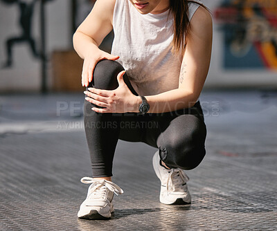 Closeup of one caucasian woman holding her sore knee while exercising in a gym. Female athlete suffering with painful leg injury from fractured joint and inflamed muscles during workout. Struggling with stiff body cramps causing discomfort and strain