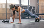 One fit young hispanic woman doing bodyweight push up exercises while exercising in a gym. Focused female athlete doing press ups and a plank hold to build muscle, enhance upper body, strengthen core and increase endurance during a training workout