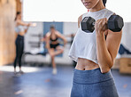 Closeup of one fit caucasian woman doing bicep curl exercises with a dumbbell while training in a gym. Female athlete challenging herself by lifting heavy weights to build muscle and endurance during workout in a fitness centre
