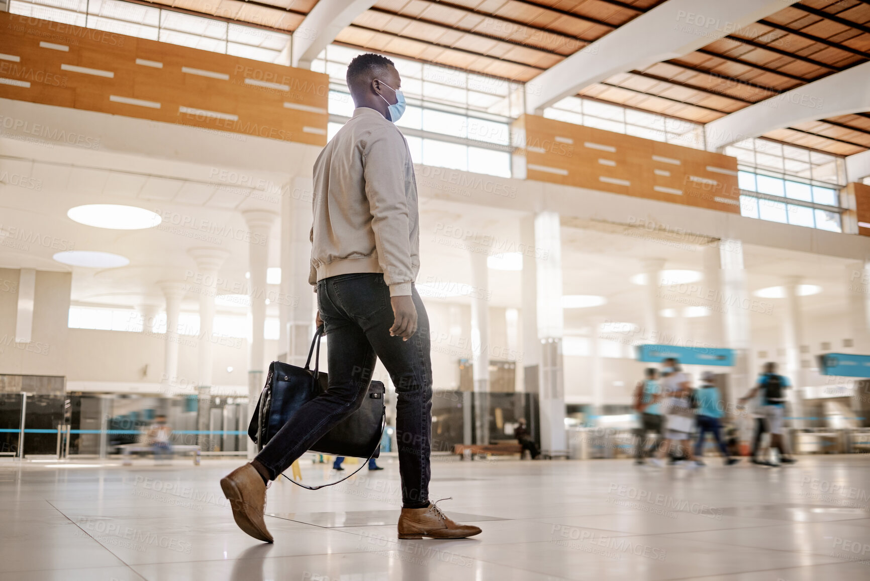 Buy stock photo Rear view of African american businessman travelling alone and walking in a train station while wearing a mask for protection against coronavirus