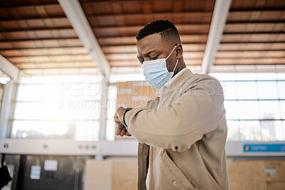 Buy stock photo Black Black Rear view of African american businessman travelling alone and standing in a train station while checking his travel times on his watch