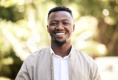 Portrait of a young businessman standing in the street in the city smiling and looking happy on a sunny day. African american male expressing happiness on his face